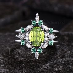 an oval shaped green and white diamond ring on a black stone surface with diamonds surrounding it