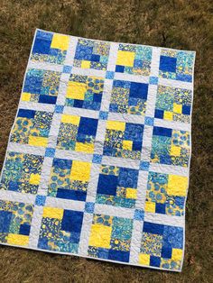 a blue and yellow quilt on the grass