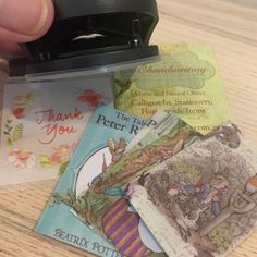 a hand is holding a stamper with some cards in it on a wooden table