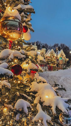 a christmas tree with lights and ornaments in the snow