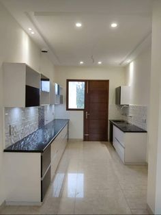 an empty kitchen with white cabinets and black counter tops is seen in this image from the hallway