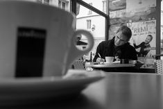 a man sitting at a table writing in front of a coffee cup and saucer