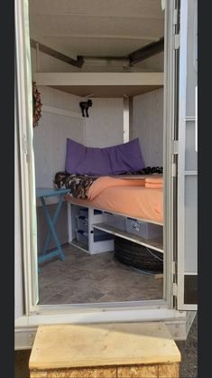 the inside of a small trailer with a bed and storage space in it's door