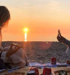 two people eating pizza on the beach at sunset