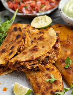 several quesadillas are stacked on top of each other with lime wedges