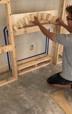 a man is working on some kind of bunk bed frame in the process of being built