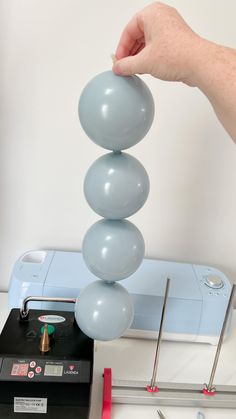 a person is placing three balloons on top of each other in front of a projector