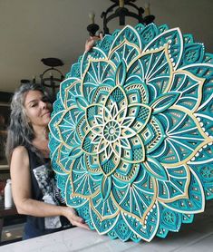 a woman holding up a large blue and gold paper art piece