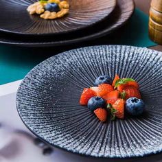 a plate with berries and walnuts on it sitting on a table next to other plates