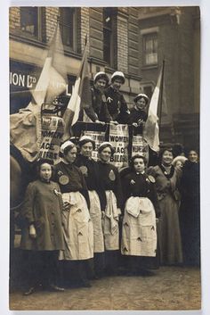 a group of women standing next to each other in front of a building with flags