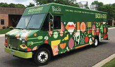 a green food truck parked in front of a building