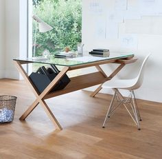 a desk with a glass top sitting in front of a window