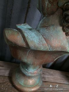 an old bronze statue is sitting on a wooden table