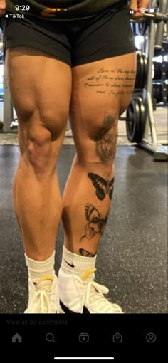 a person with tattoos on their legs standing next to a barbell