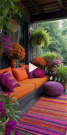 an outdoor living area with orange and purple furniture, potted plants, and colorful rugs