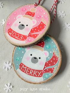 two wooden ornaments with polar bears on them, one is merry and the other has snowflakes