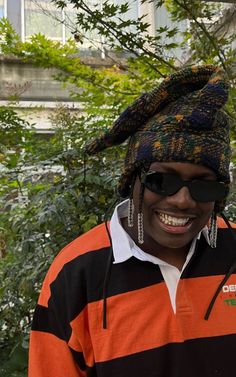 a man in an orange and black striped shirt is smiling with sunglasses on his head