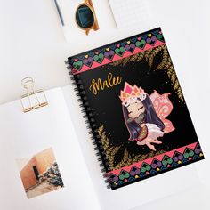 a spiral notebook with an image of a princess sitting on top of it next to other items