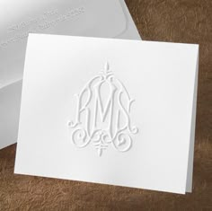 a white card with a monogrammed design on the front and back of it