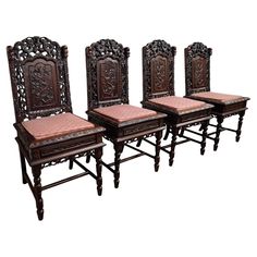 four carved wooden chairs sitting side by side