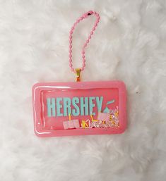 the name hershey is hanging from a pink plastic sign on a white fur surface