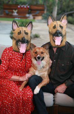 a man and woman sitting on a couch with two dogs wearing masks over their heads