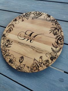 a personalized wooden plate with roses on it sitting on a blue wood table top