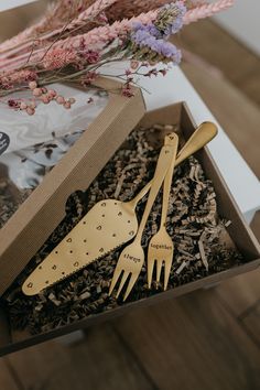 two forks and spoons in a box with dried flowers