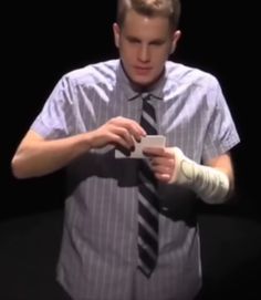 a man in a shirt and tie holding a cell phone with bandages on his arm