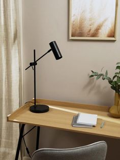 a desk with a lamp and some books on it next to a potted plant