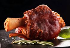 a piece of meat sitting on top of a wooden cutting board next to green leaves