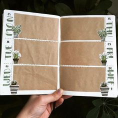 a hand holding up an open book with pictures on the pages and plants in it