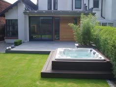 a large hot tub sitting in the middle of a lush green yard next to a house