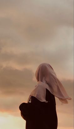 a woman with a white veil on her head looking at the sky