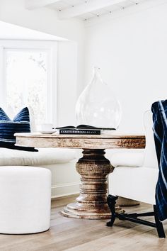 a living room filled with furniture and a round table in front of a window on top of a hard wood floor