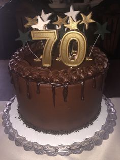 a chocolate birthday cake with gold stars and the number seventy on it's top