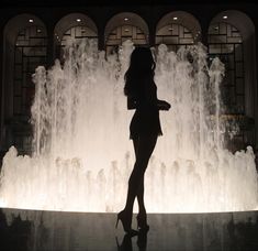 a woman standing in front of a water fountain