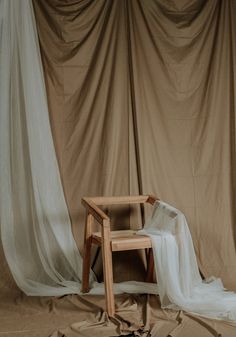 a chair sitting on top of a wooden floor next to a white cloth covered wall