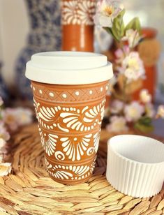 two coffee cups sitting on top of a wicker tray next to flowers and vases