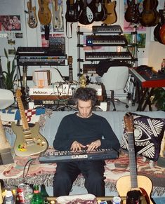 a man sitting on top of a couch playing an electronic keyboard