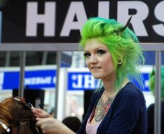 a woman with green hair is getting her hair styled by another person at an event