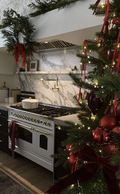 a christmas tree with red and gold ornaments is in the corner of a kitchen, next to an oven