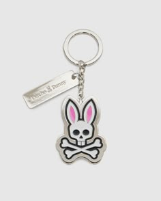 Introducing the CLASSIC BUNNY KEYCHAIN - B6A372E200 from Psycho Bunny, a fashionable metal accessory showcasing a cartoon bunny skull and crossbones design with distinctive pink ears. This practical everyday keychain features a sleek rectangular tag engraved with Psycho Bunny. Complemented by a silver-colored chain and keyring, it adds a chic touch to your essentials. Bunny Keychain, Athlete Gifts, Bunny Logo, Soft Enamel, Family Set, Red Shop, Nickel Silver, 50th Gifts, Metal Plate