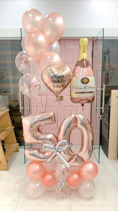 balloons and champagne are on display in front of a pink door with the number 50