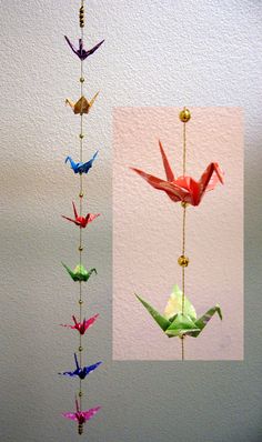 three different colored origami birds hanging from a string on the wall next to each other