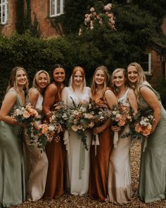 a group of women standing next to each other holding bouquets in front of a building