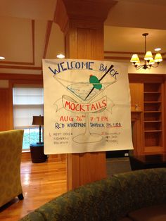 a welcome sign hanging from the side of a wooden pole in a room with wood flooring