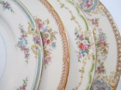 four plates with floral designs on them sitting side by side