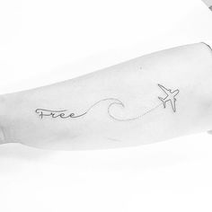 an airplane is flying over the water and waves tattoo on the arm, which reads free