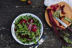 a salad with beets in a bowl next to a knife and fork